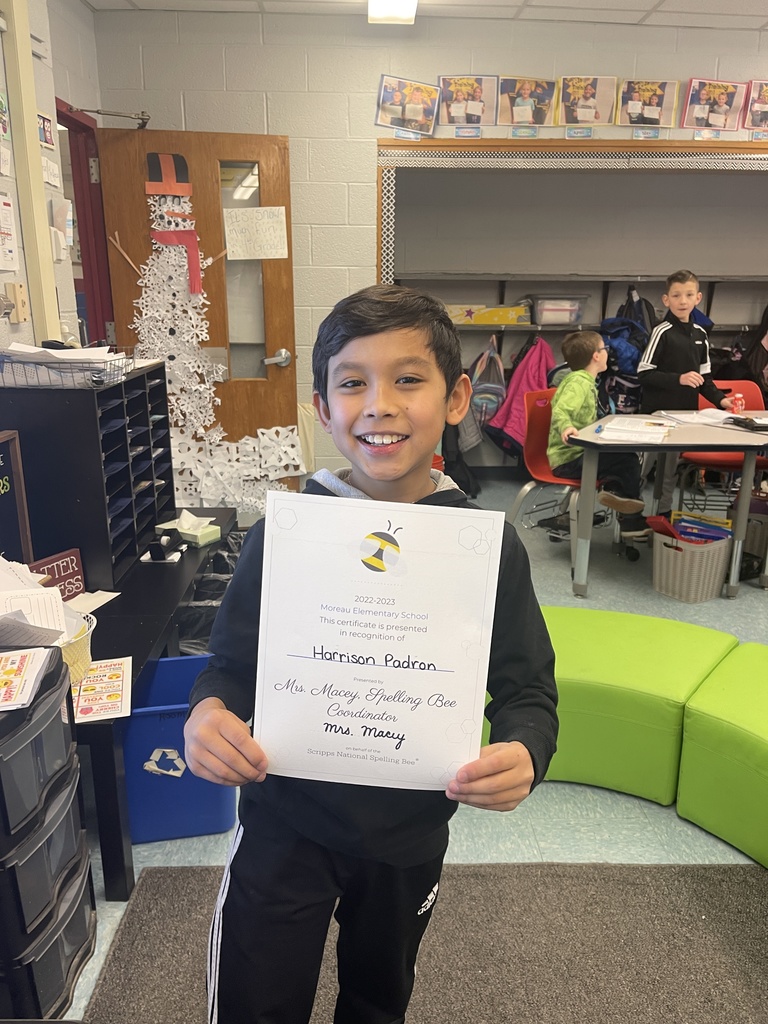 Student holds a sheet of paper proclaiming them spelling bee champion