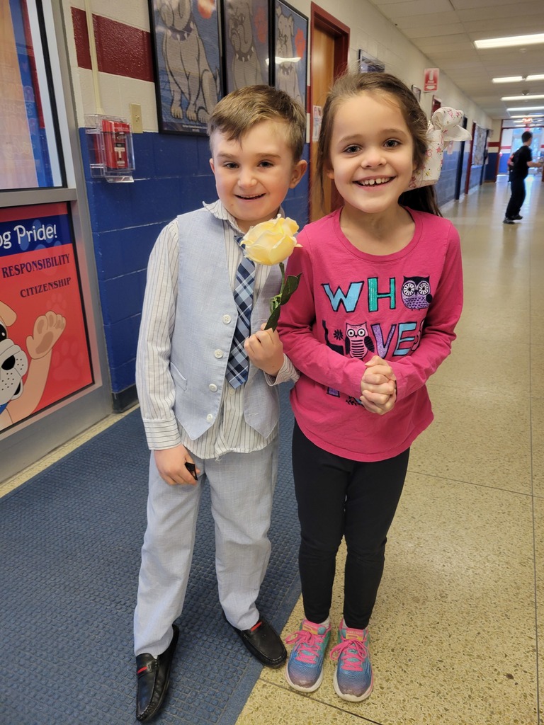 A student holds a white rose next to another student