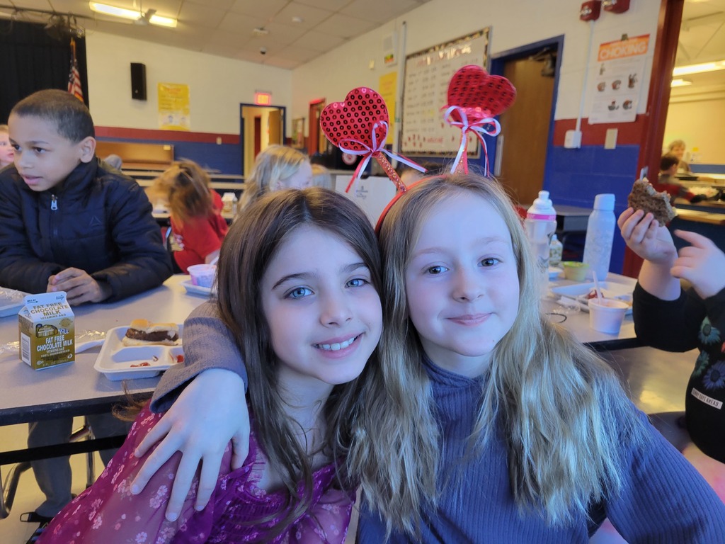 Two students pose, one wearing a heart shaped headband