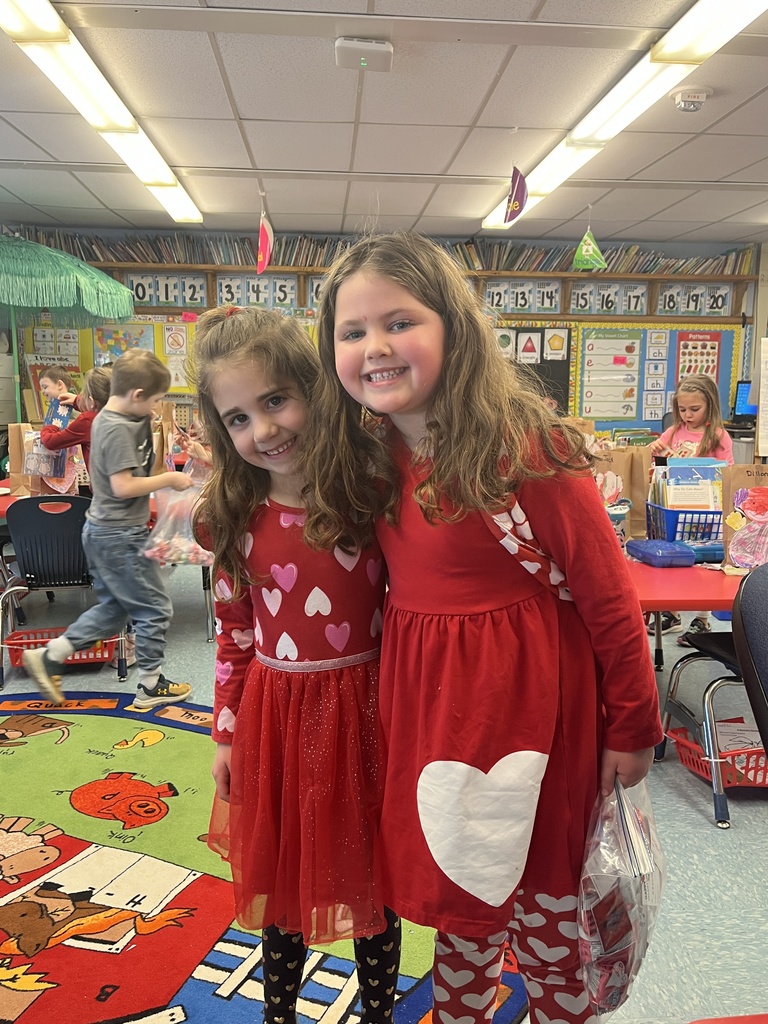 Two girls wear red dresses with heart prints.